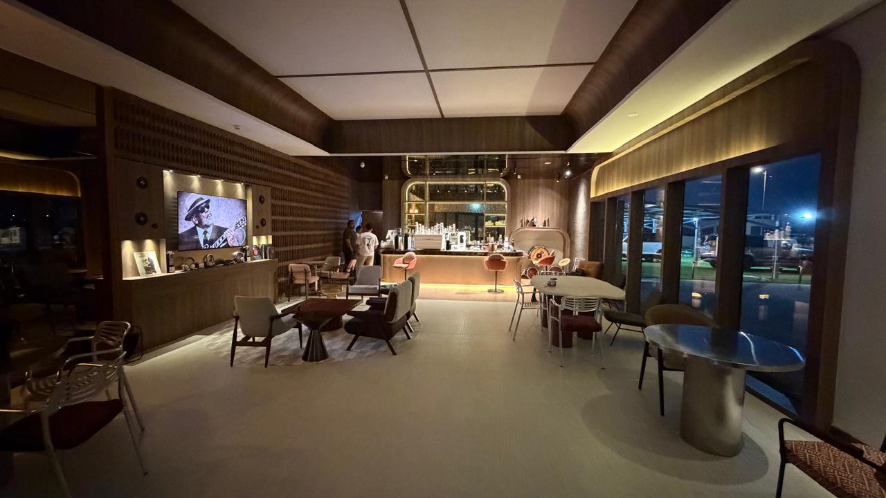 Café interior at night with timber walls, a lit bar at the far end and lounge seating